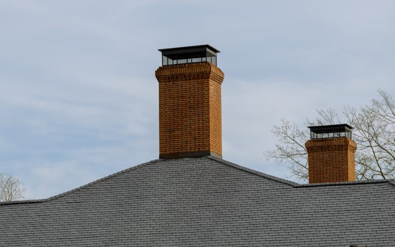 Brick chimney stack on modern contemporary house roof top modern pipe