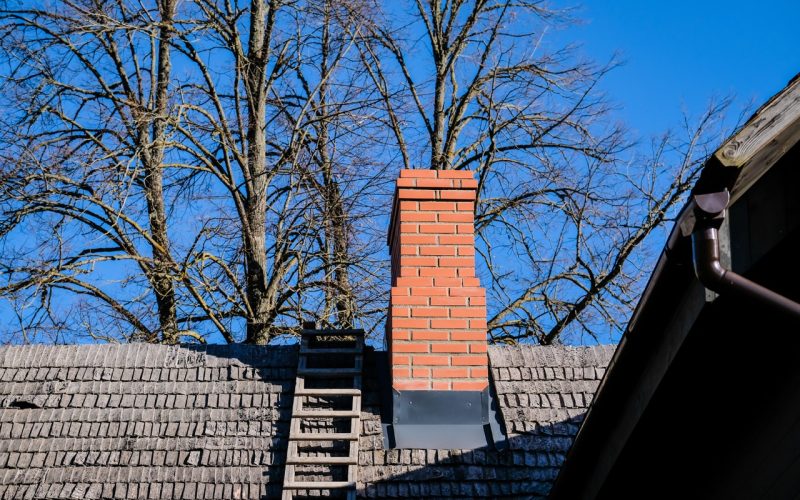 Wooden roof of a detached house with a skylight and red brick chimney against the sky. High quality photo